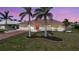 Inviting home featuring a bright red door, lush lawn, mature palm trees, and paver driveway leading to a two car garage at 530 Matares Dr, Punta Gorda, FL 33950