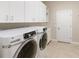 Washer and dryer next to white cabinets in this bright tiled laundry room at 8725 Amaretto Ave, Sarasota, FL 34238