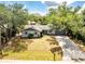 Aerial view of a home with mature trees, a well-manicured lawn, a spacious driveway, and a charming exterior at 1173 Belmar Ave, Port Charlotte, FL 33948