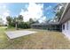 Wide backyard view with basketball court and screened in pool area, trees and partial house view at 1173 Belmar Ave, Port Charlotte, FL 33948