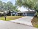 Home exterior featuring a gray roof, shutters, stone accents, a well-manicured lawn, and a spacious driveway at 1173 Belmar Ave, Port Charlotte, FL 33948