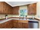 Close-up of kitchen featuring wood cabinets, stainless steel dishwasher, and a double sink at 1173 Belmar Ave, Port Charlotte, FL 33948