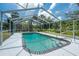 A screened-in swimming pool with steps and railing for accessibility and a view of the well maintained lawn surrounding the pool at 1173 Belmar Ave, Port Charlotte, FL 33948