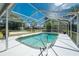 A clear screened-in pool with access ladder and a surrounding white patio area and view of the exterior of the home at 1173 Belmar Ave, Port Charlotte, FL 33948