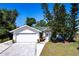 Charming single-story home with a white exterior, green roof, well-maintained lawn, and mature landscaping at 1381 Fargo St, Port Charlotte, FL 33952