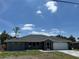 Charming single-story home with a gray exterior, arched windows, attached garage, and well-maintained lawn at 21215 Cottonwood Ave, Port Charlotte, FL 33952