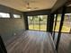 Bright Florida room with gray wood-look floors, multiple sliding glass doors, and ceiling fan at 21215 Cottonwood Ave, Port Charlotte, FL 33952