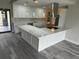 Modern kitchen featuring sleek white cabinets, a large island, stainless steel appliances, and gray flooring at 21215 Cottonwood Ave, Port Charlotte, FL 33952