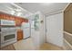 Compact kitchen features tile flooring, white appliances and wood cabinets by the entrance at 25225 Rampart Blvd # 1607, Punta Gorda, FL 33983