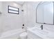Modern bathroom features a tub and shower combination with sleek white tile, black fixtures, and an arched mirror at 3140 Lopinto St # 1, North Port, FL 34287