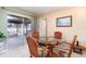 Cozy dining area with a glass-top table and wicker chairs, situated next to sliding glass doors to the backyard at 3187 Elkcam Blvd, Port Charlotte, FL 33952