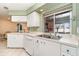 Bright kitchen with white countertops, cabinets, stainless steel sink and a large window offering scenic views at 3187 Elkcam Blvd, Port Charlotte, FL 33952