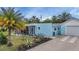 Charming light-blue home featuring a screened in porch, gravel driveway and tropical landscaping at 3215 Cedarbrook Dr, Punta Gorda, FL 33982