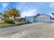 Charming light-blue single-story home with a gravel driveway and detached one car garage, accented by mature palm trees at 3215 Cedarbrook Dr, Punta Gorda, FL 33982