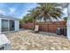 Cozy outdoor paver patio featuring privacy fence with palm trees and a single chair for relaxation at 3215 Cedarbrook Dr, Punta Gorda, FL 33982
