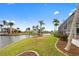 Scenic backyard featuring a canal view, lush lawn, and tropical palm trees near a screened lanai at 3705 Toulouse Ct, Punta Gorda, FL 33950