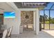Outdoor kitchen on a screened-in patio featuring a stainless-steel grill, sink, mini-fridge, and beach view on the TV at 4001 La Costa Island Ct, Punta Gorda, FL 33950