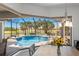 A view of a large, screened-in pool with tropical landscaping and golf course views as seen from the kitchen nook at 4001 La Costa Island Ct, Punta Gorda, FL 33950