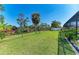 Large backyard with lush green grass, secure fencing, and a serene pond view at 420 Wabash Ter, Port Charlotte, FL 33954