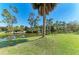 Scenic view of the tranquil pond from the lush backyard, framed by swaying palms and lush greenery at 420 Wabash Ter, Port Charlotte, FL 33954