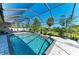 Screened-in pool area features a beautifully tiled pool, well-manicured landscaping, and a comfortable seating area at 420 Wabash Ter, Port Charlotte, FL 33954