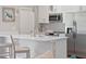 Modern kitchen with stainless steel appliances, white cabinetry, quartz countertops, and bar seating at 4343 Killdeer Ter, North Port, FL 34288