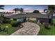 Charming home at dusk with well-manicured front yard, palm trees, fountain, and circular paver driveway at 505 Via Cintia, Punta Gorda, FL 33950