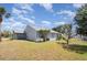 Light blue house with neutral trim surrounded by a lawn, trees, and a bright blue sky at 5121 Chaves Cir, Port Charlotte, FL 33948