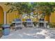 Community grilling station with multiple grills for resident use with a trash receptacle nearby and green foliage at 93 Vivante Blvd # 9344, Punta Gorda, FL 33950
