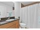 Clean bathroom featuring a granite countertop, wooden cabinetry and tub with shower at 12857 Pinnacle Ln, Venice, FL 34293
