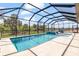 Beautiful screened pool with a spa and a view of the lush, green landscape surrounding the property at 12857 Pinnacle Ln, Venice, FL 34293