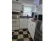 Kitchen features white cabinets and a black and brown checkerboard floor at 1457 Sheehan Blvd, Port Charlotte, FL 33952