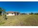 Expansive grassy yard and exterior view of covered lanai on tan single story home with blue sky at 1606 Navigator Rd, Punta Gorda, FL 33983