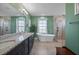 Gorgeous bathroom featuring double sinks, a soaking tub, stand-alone shower and calming, green walls at 1606 Navigator Rd, Punta Gorda, FL 33983