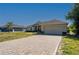Paver driveway leads up to a tan home with a two-car garage and manicured lawn under a clear blue sky at 1606 Navigator Rd, Punta Gorda, FL 33983