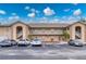 Beige condo building featuring covered stairwells, balconies, a parking lot, and tropical landscaping at 175 Kings Hwy # B2 1522, Punta Gorda, FL 33983