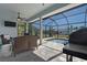Relaxing screened-in patio with comfortable seating, ceiling fan, TV, and a view of the pool at 2229 Wakefield St, Port Charlotte, FL 33948
