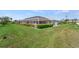 Expansive backyard featuring a screened lanai, lush green grass, and manicured shrubbery at 229 Sportsman Rd, Rotonda West, FL 33947
