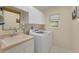 Bright laundry room with a utility sink and a stacked washer and dryer set with overhead cabinets at 229 Sportsman Rd, Rotonda West, FL 33947