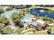 Aerial view of the community pool, shuffleboard, and tennis courts surrounded by greenery and trees at 23465 Harborview Rd # 842, Port Charlotte, FL 33980
