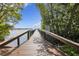 A long wooden dock leads into the sea, framed by lush green trees against a clear blue sky at 23465 Harborview Rd # 842, Port Charlotte, FL 33980