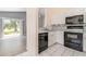 Kitchen with sleek black appliances and white cabinets; view to an adjacent living space at 242 Seminole Nw Blvd, Port Charlotte, FL 33952