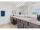 Bathroom featuring double sinks, granite countertops, and large mirror with modern light fixture at 3476 Brewster Rd, North Port, FL 34288