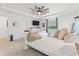 Bright main bedroom featuring a ceiling fan, white walls, TV, and large window with blue curtains at 3476 Brewster Rd, North Port, FL 34288