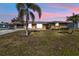 Charming single-story home with a well-maintained lawn, palm trees, and a cozy seating area on the porch at 3480 Pinetree St, Port Charlotte, FL 33952