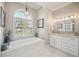 Bright bathroom with a white tub beneath a window and a vanity with marble counters at 529 La Caruna Ct, Punta Gorda, FL 33950