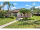 This exterior view features a well-maintained lawn, complemented by lush tropical landscaping, including mature palm trees at 5390 Brassy Loop, North Port, FL 34287