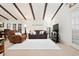 Inviting living room with vaulted ceilings, wooden beams, neutral carpet, comfortable brown leather seating, and decorative turtle art at 5390 Brassy Loop, North Port, FL 34287