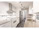 Updated galley kitchen featuring white cabinets, mosaic tile backsplash, and sleek stainless hood at 6329 David Blvd, Port Charlotte, FL 33981