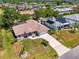 Aerial view of a landscaped home with a long driveway, screened pool and lush greenery at 452 Greenwich Nw Ave, Port Charlotte, FL 33952